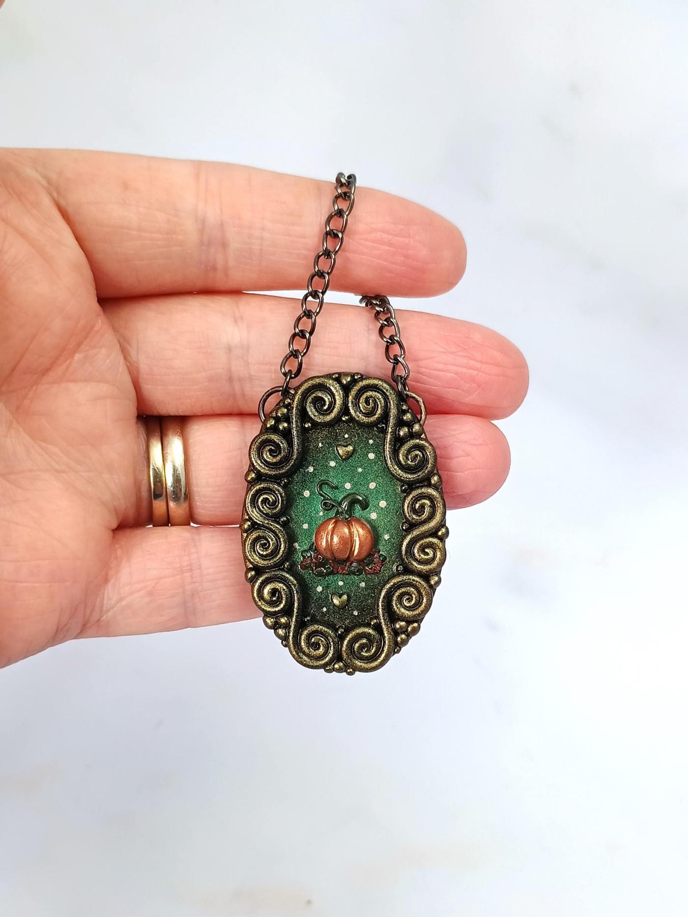 Polymer clay mini art being held. The focal point of the picture is a pumpkin