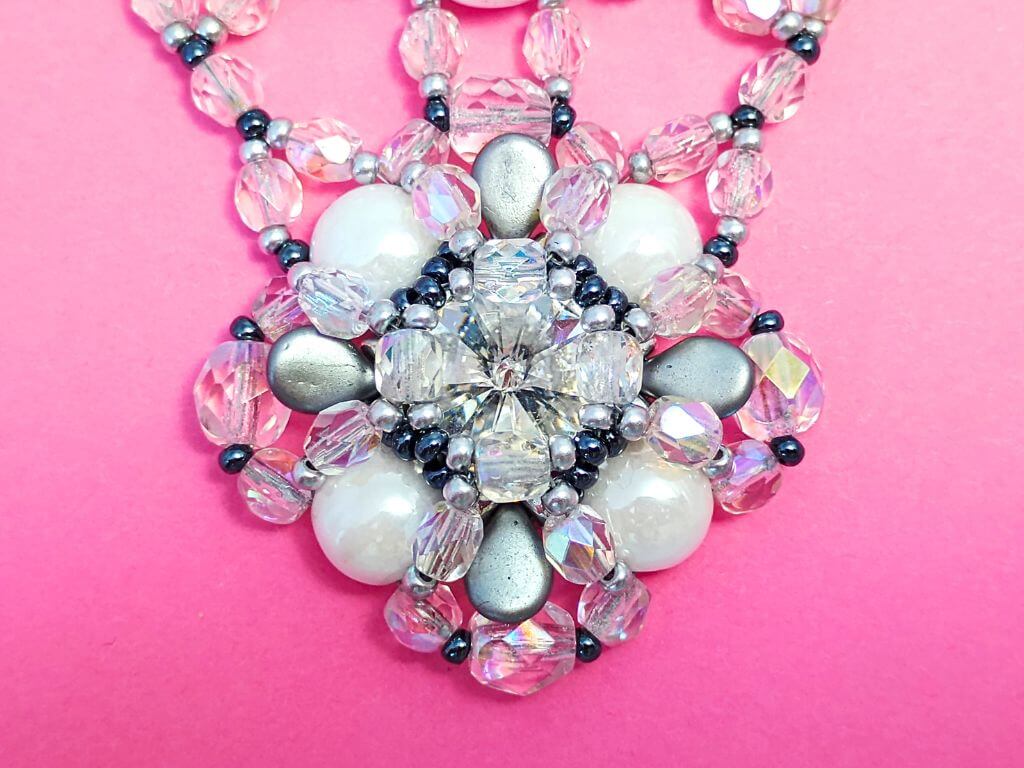 A close up of a beaded bezel pendant with rivoli focal point