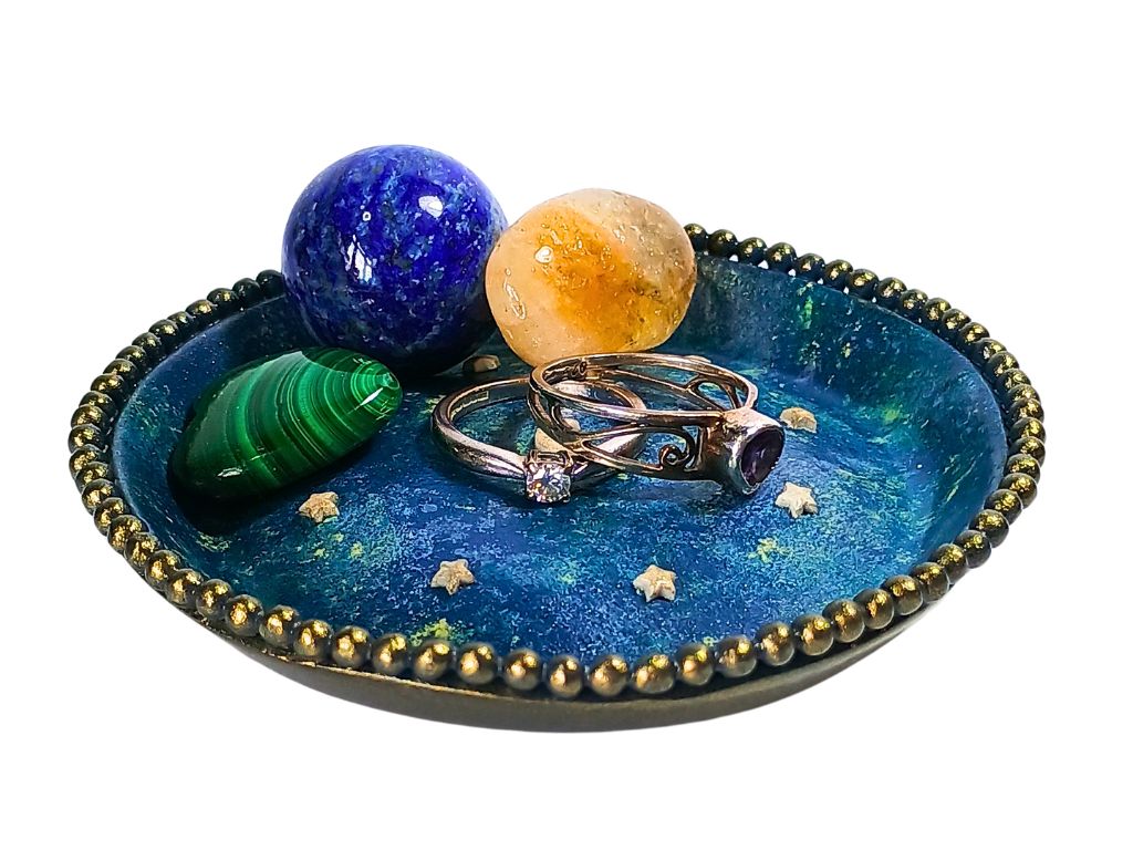 A polymer clay ring dish with rings and crystals in it