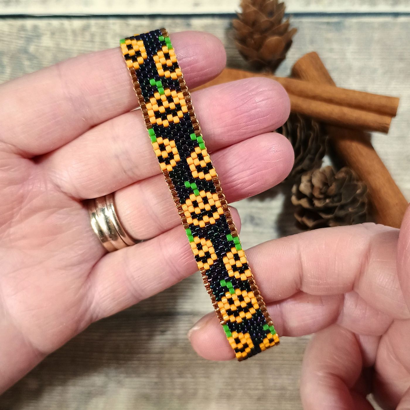 A beaded bracelet with a pumpkin design being held.