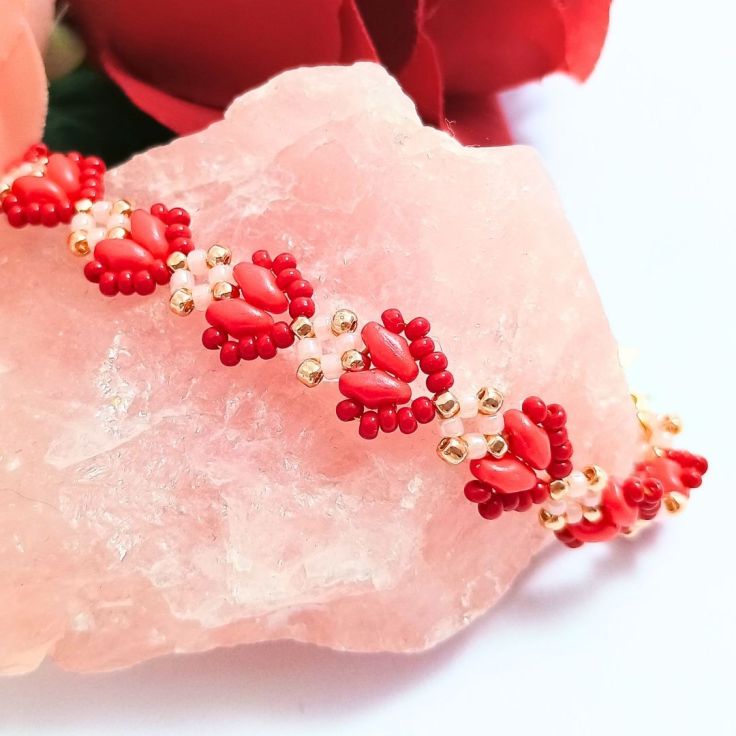 A finished beaded heart bracelet sitting on a piece o rose quartz