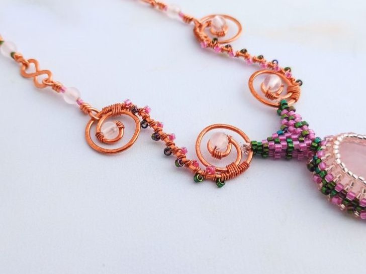 A close up of a copper beaded swirl with delica bead accents.