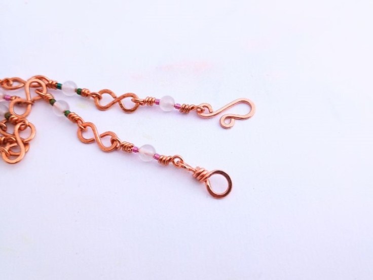 A copper wire chain with delica beads and rose quartz beads. This is finished with a copper wire hook fastening