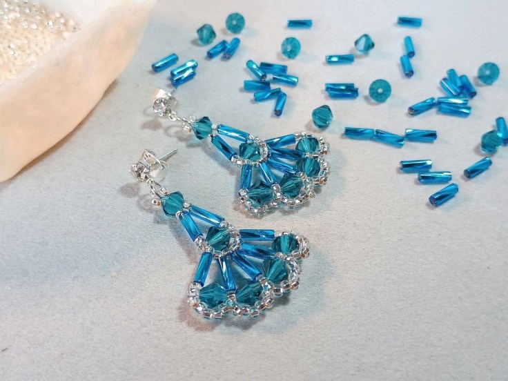 Bugle bead and bicone bead earrings sitting on a beading mat